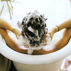 Frau mit shampooniertem Haar in der Wanne